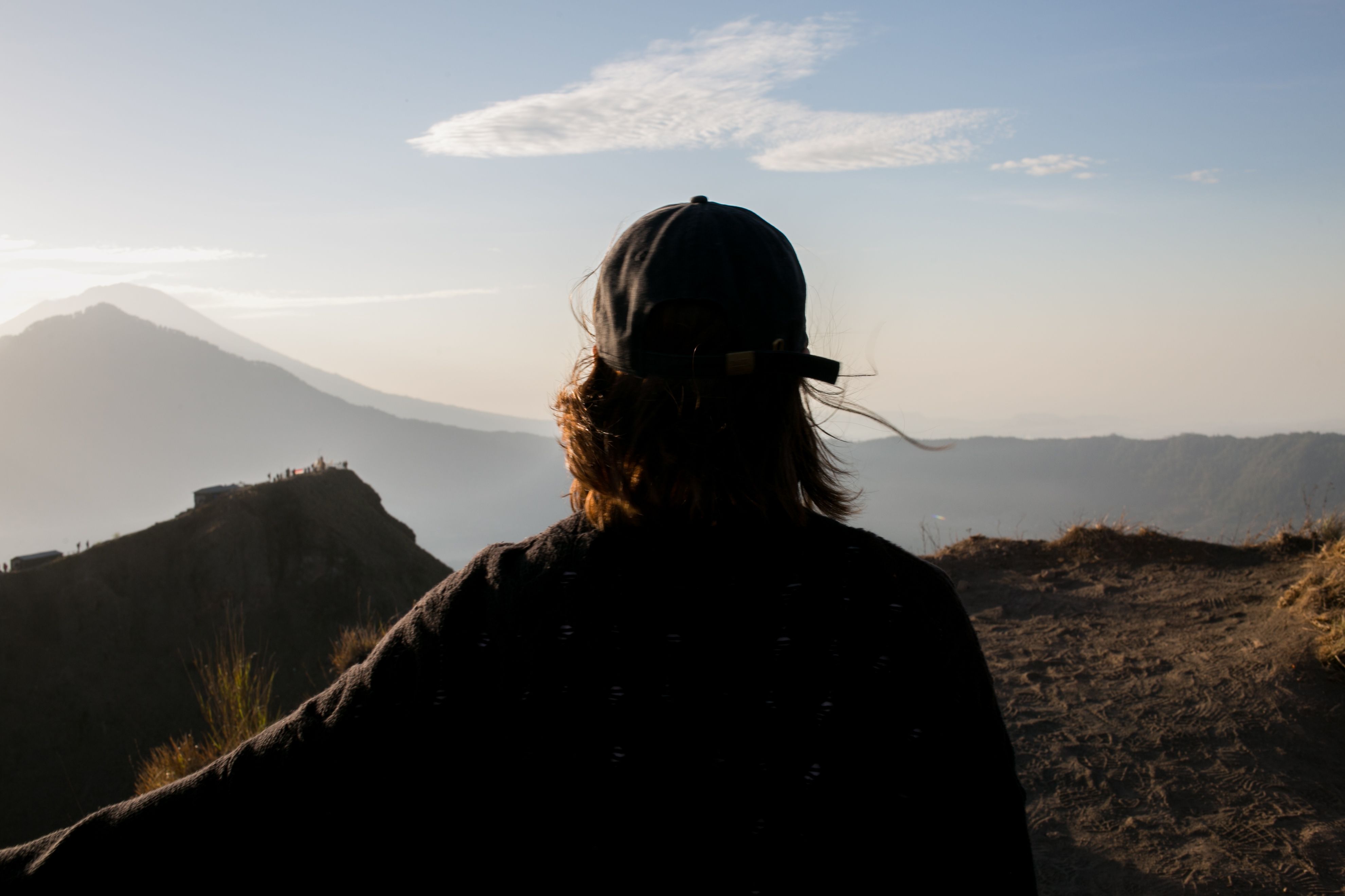 一名徒步旅行者站在山峰上，迎着晨光，心怀冒险之感拥抱这片宁静