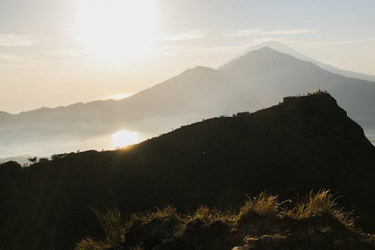 Breathtaking view of a sunrise casting light over silhouetted mountains and a tranquil lake.