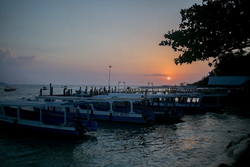 Moored boats in calm lagoon at sunset