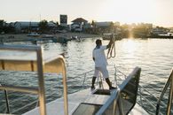 Man on yacht in bay at sunset