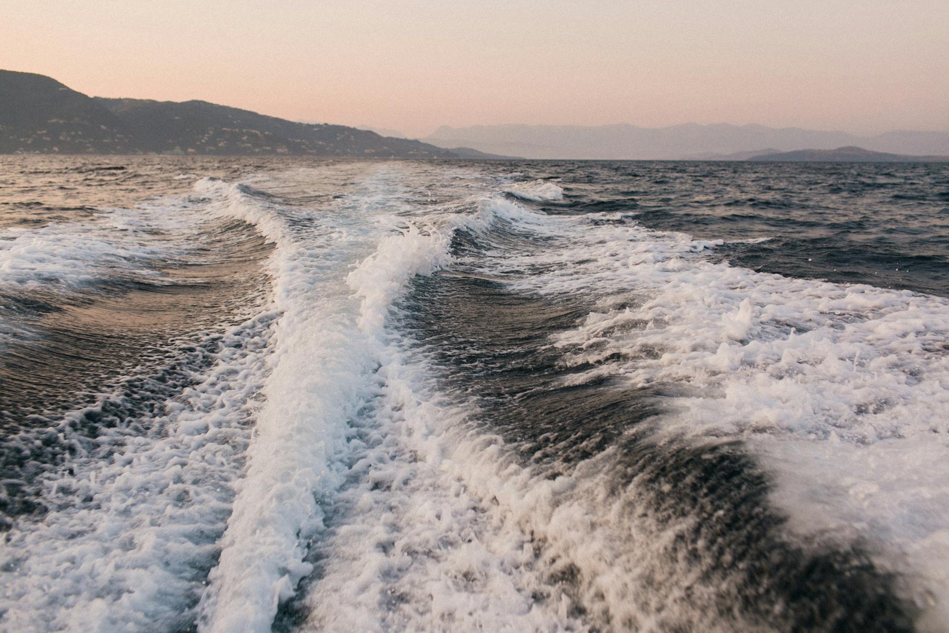 White splashes and foamy trails after motorboat on rough water of sea in dusk