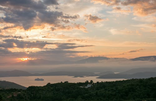 Calm scenery of remote house in green hills against majestic valley of sea bays and hills in sundown