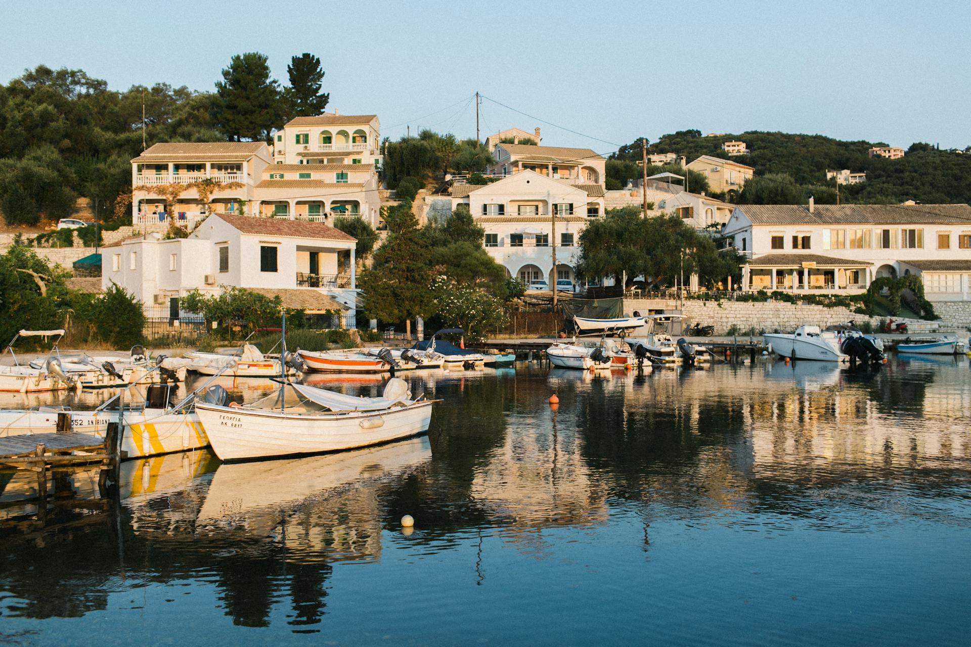A picturesque coastal village with boats docked by the serene waterfront at sunset.