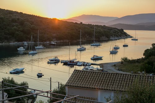 Smooth sea water with floating yachts and green hilly seashore in sunset light