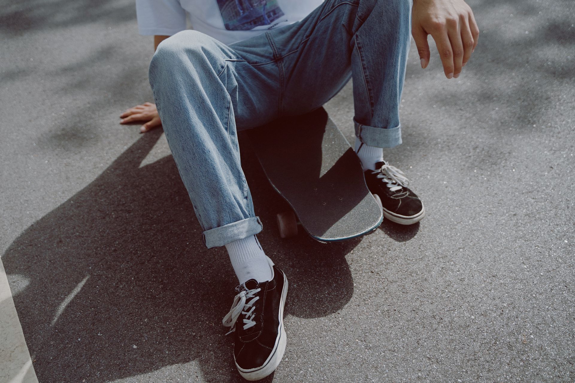 Person in Blue Denim Jeans Sitting on Skateboard