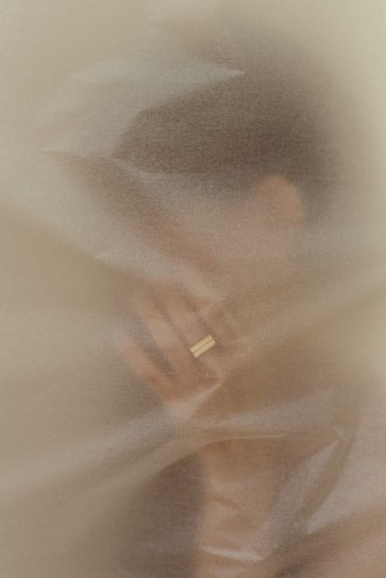 An abstract portrait with soft style, featuring a hand with a ring through translucent material.