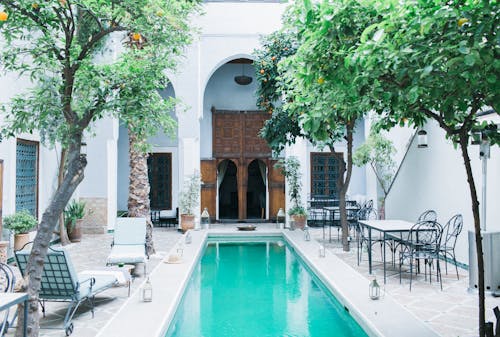 Exterior of patio with wooden doorway and tangerine trees near swimming pool and furniture