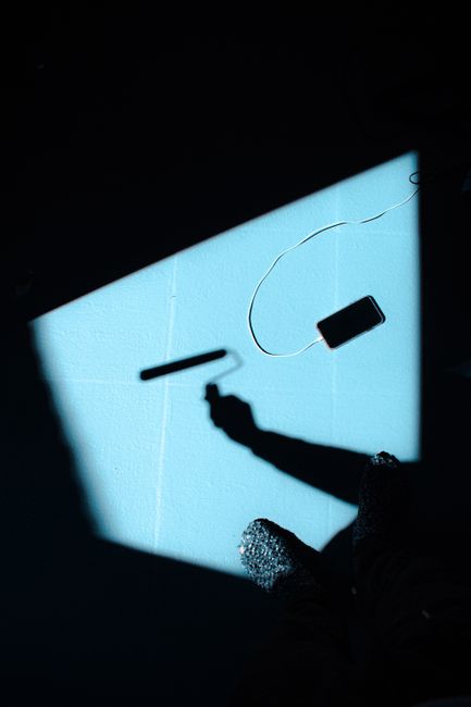 Creative composition of shadows with a smartphone and paint roller on a blue background.