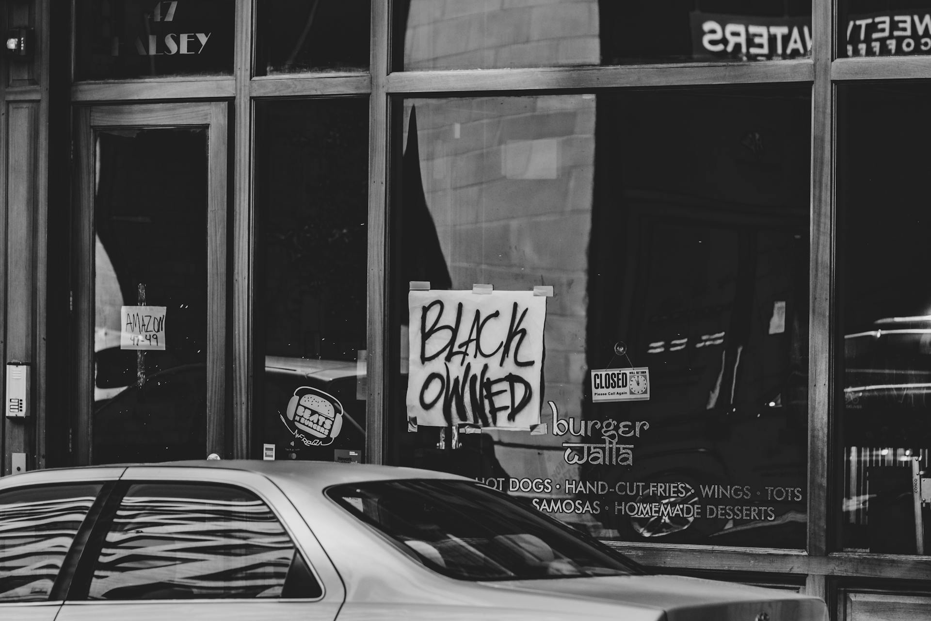 Black-owned business sign on a city store window with reflections in black and white.