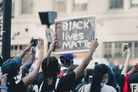 Crowd of people standing on street and protesting racial injustice with placards in daylight