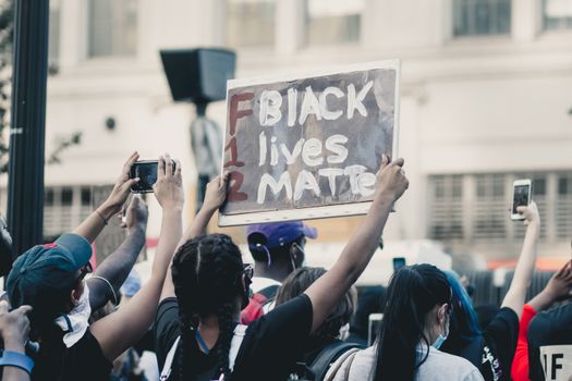 Crowd of people standing on street and protesting racial injustice with placards in daylight