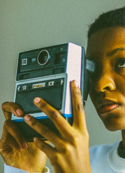 Focused black woman taking photo on retro equipment