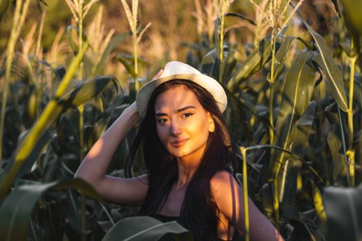A woman stands in a cornfield during golden hour, capturing natural beauty and tranquility.