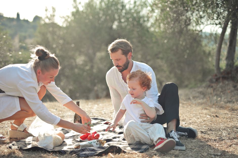 Happy family enjoying a sunny outdoor picnic in a serene natural setting.