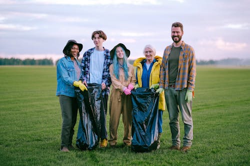 Volunteers Standing on Green Grass Field while Smiling at the Camera