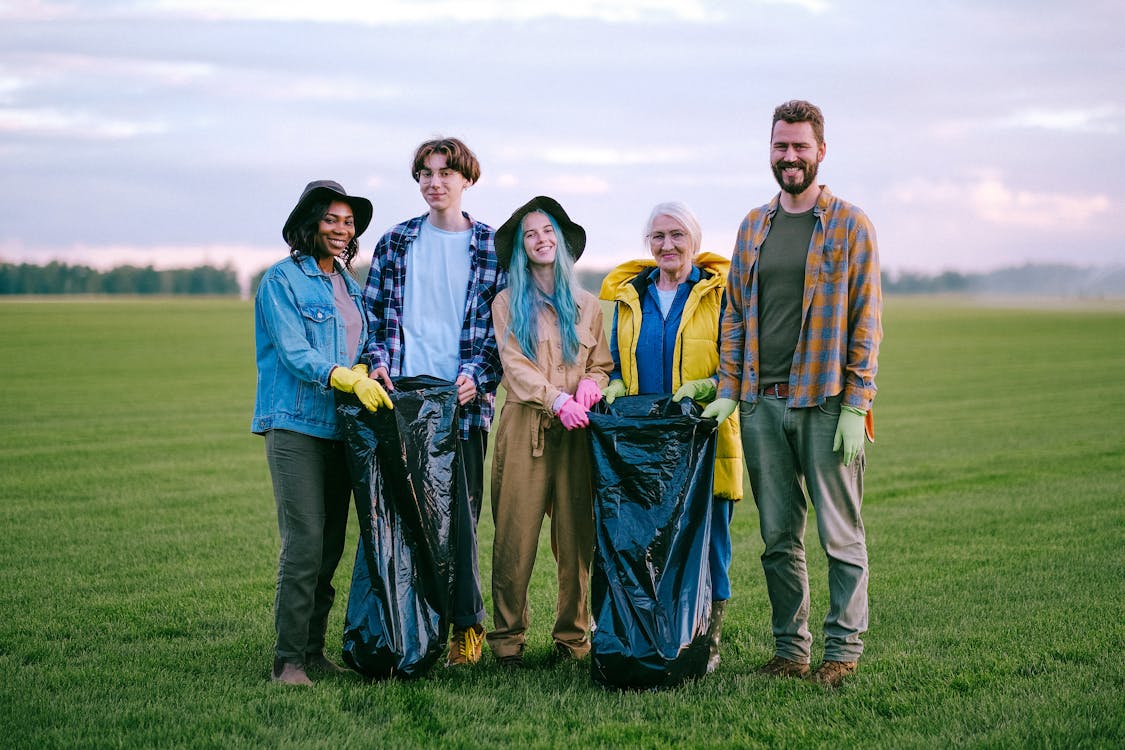 Free Volunteers Standing on Green Grass Field while Smiling at the Camera Stock Photo