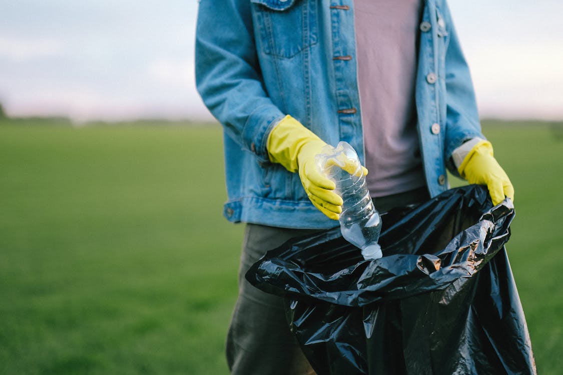 Person in Blue Denim Button Up Jacket Holding Yellow Plastic Bottle