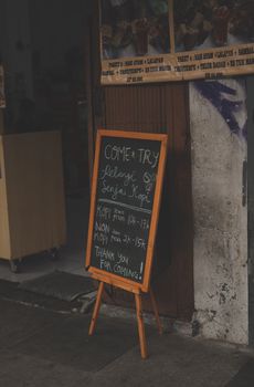 Chalkboard sign with menu outside urban coffee shop, inviting customers inside. - Fotografer Sidoarjo