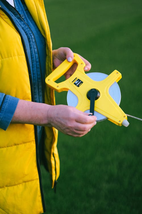 A Person Holding a Yellow Farm Tool