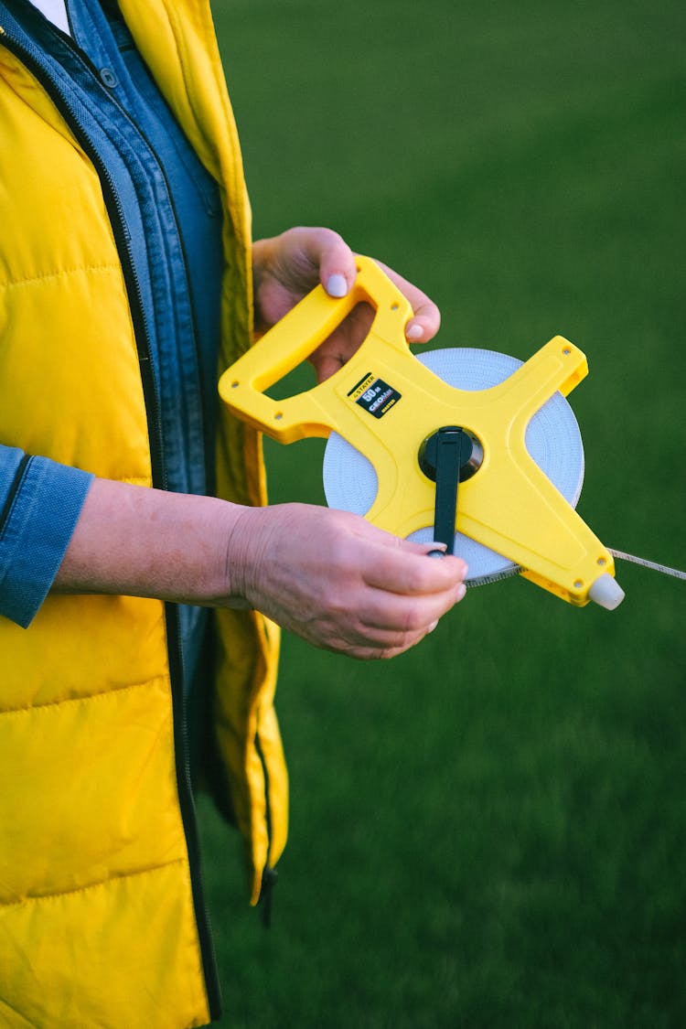 A Person Holding A Yellow Farm Tool