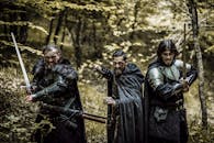 森林中，三名身穿中世纪盔甲、手持宝剑的男子正严阵以待