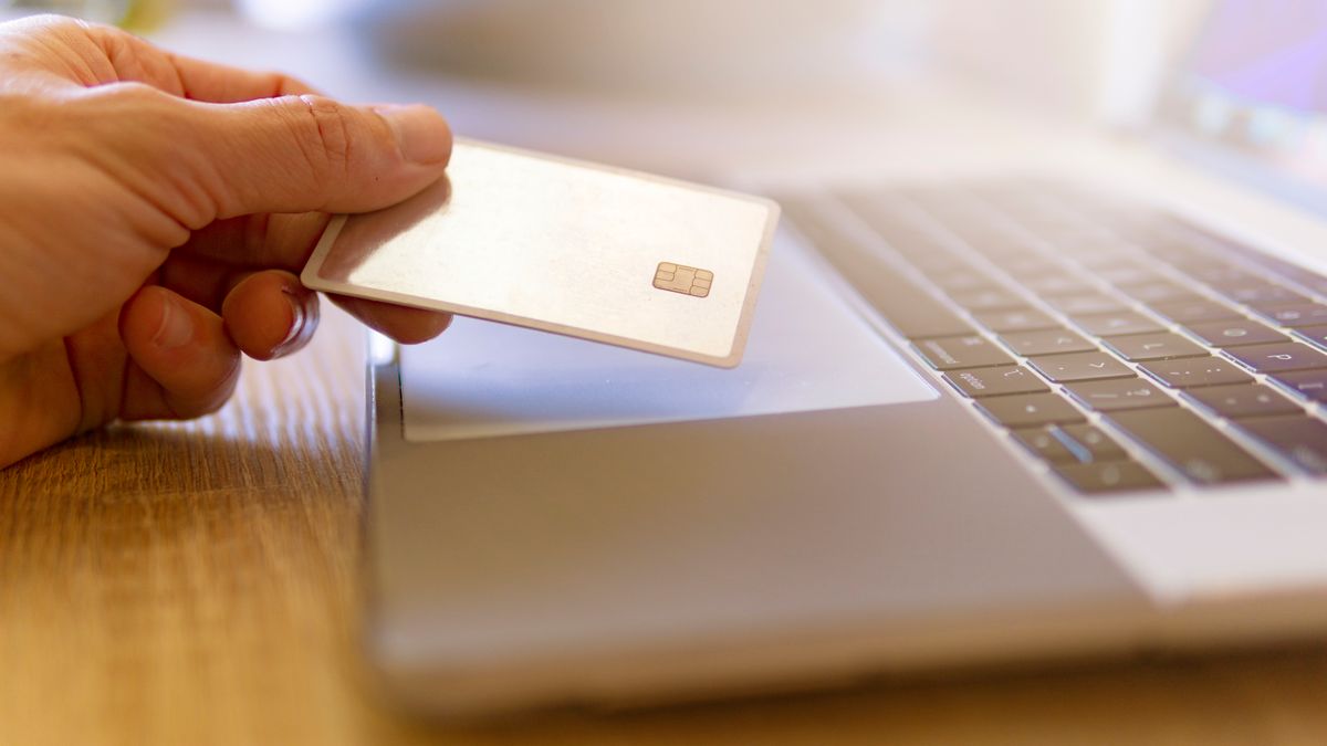 Person booking a hotel on a laptop with a credit card in hand