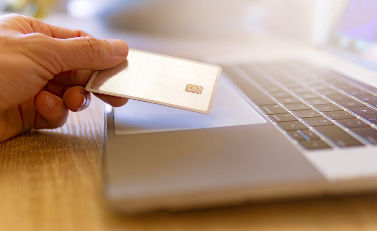 Person Holding White Card on Brown Wooden Table