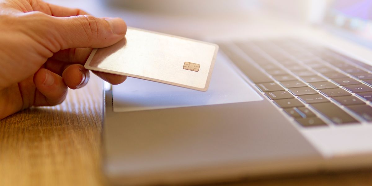 A traveler comparing hotel prices on a laptop while holding a payment card