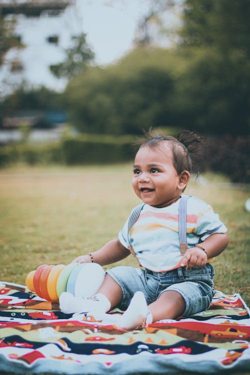 Free Selective Focus Photo of a Cute Kid in a Jumper Sitting on Cloth Stock Photo