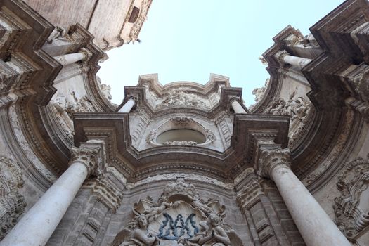 Low angle shot of a historic Baroque facade in Valencia, showcasing intricate stone carvings and columns.
