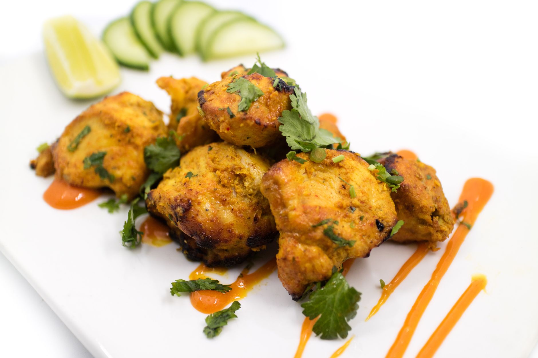 Plated vegan tandoori chicken served with lemon wedges and fresh cilantro garnish