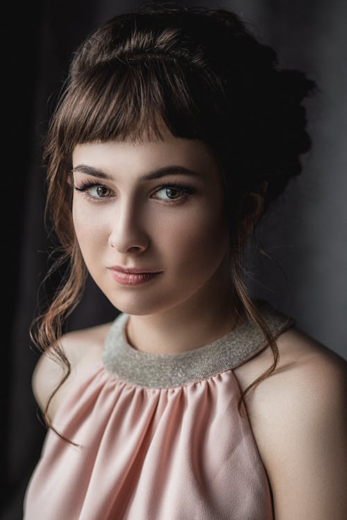 Free young female with light makeup and ceremonial hairstyle looking at camera in studio Stock Photo