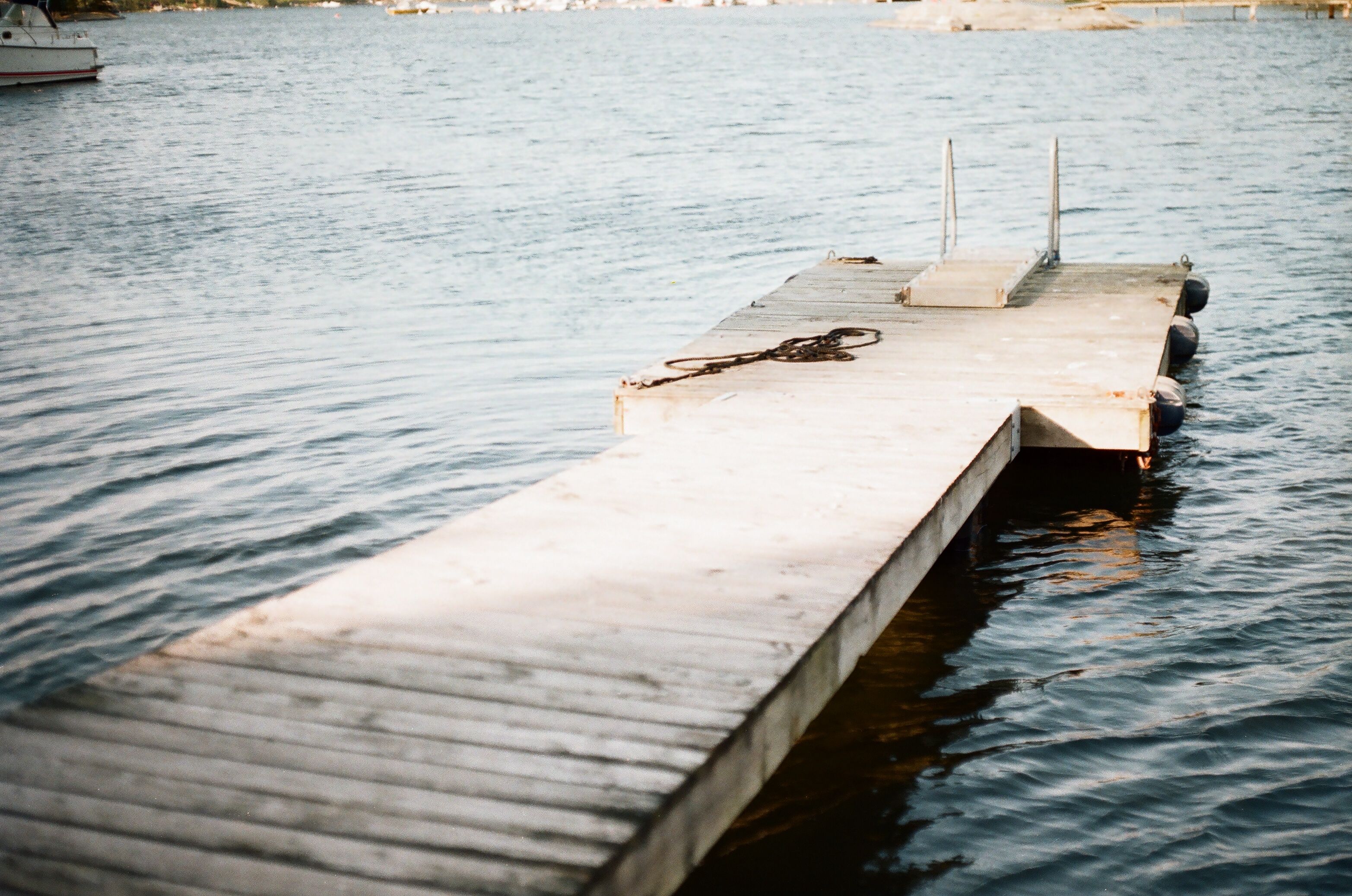 A serene wooden dock on a calm Swedish lake with gentle ripples and distant boats in Stockholm.