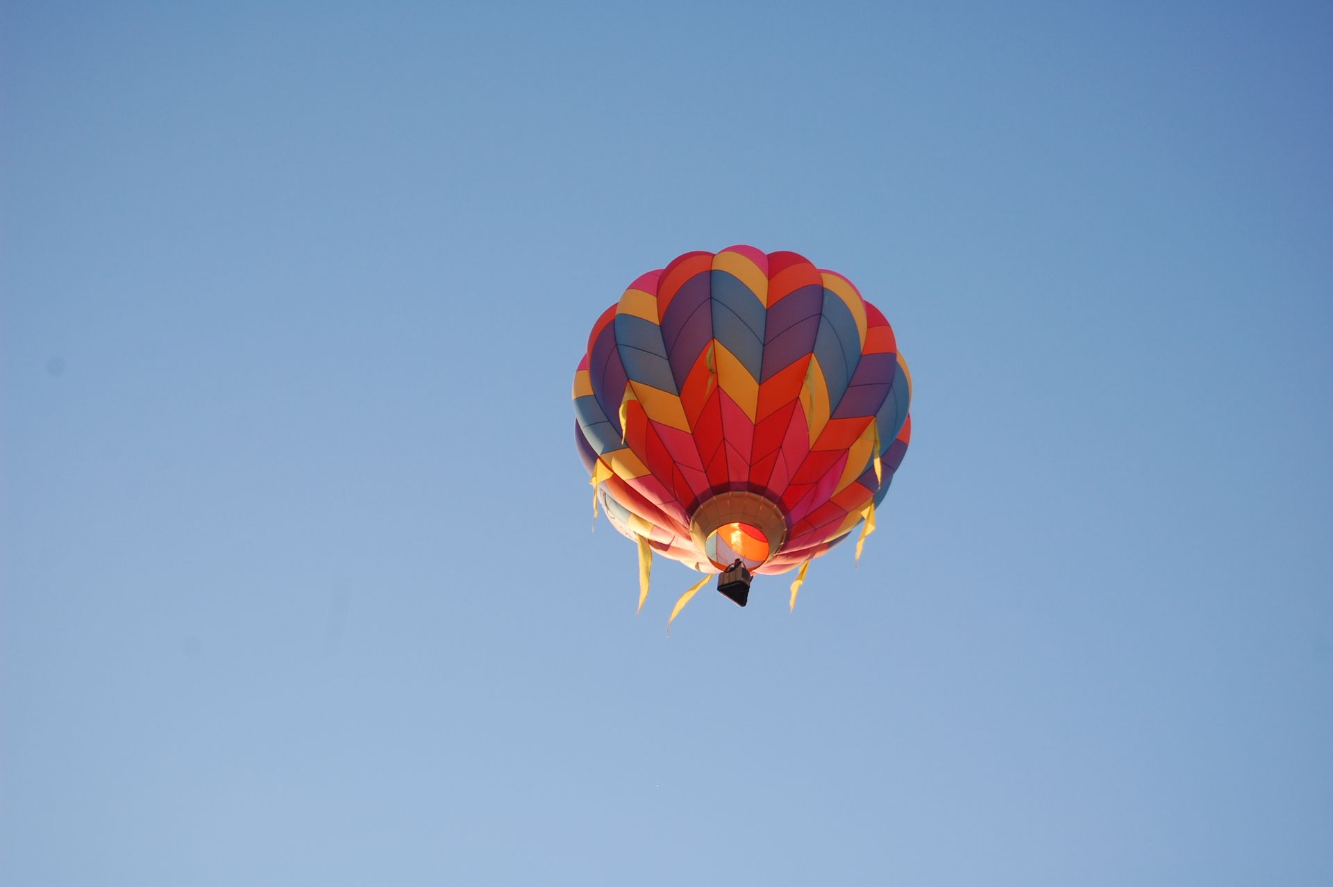 Colorful hot air balloon soaring in a clear blue sky, symbolizing freedom and adventure.