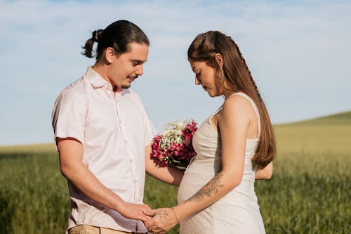 Man and Woman Holding Hands in a Green Grass Field