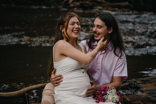 Woman in White Dress Smiling Sitting Beside a Man in Pink Shirt