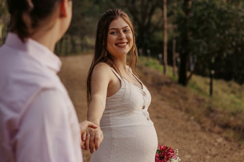 A Pregnant Woman in White Dress Smiling