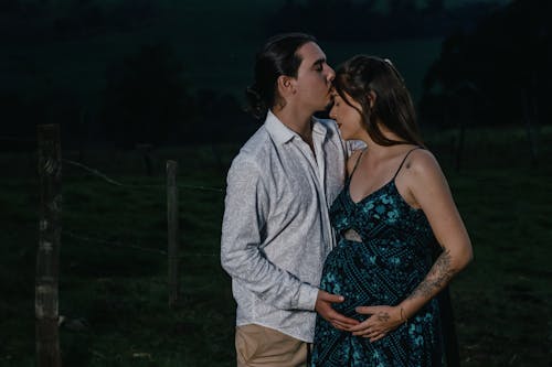 Free Man Kissing Pregnant Woman on Forehead  Stock Photo