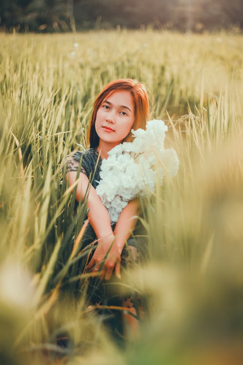 Free Dreamy ethnic woman sitting in grassy field Stock Photo