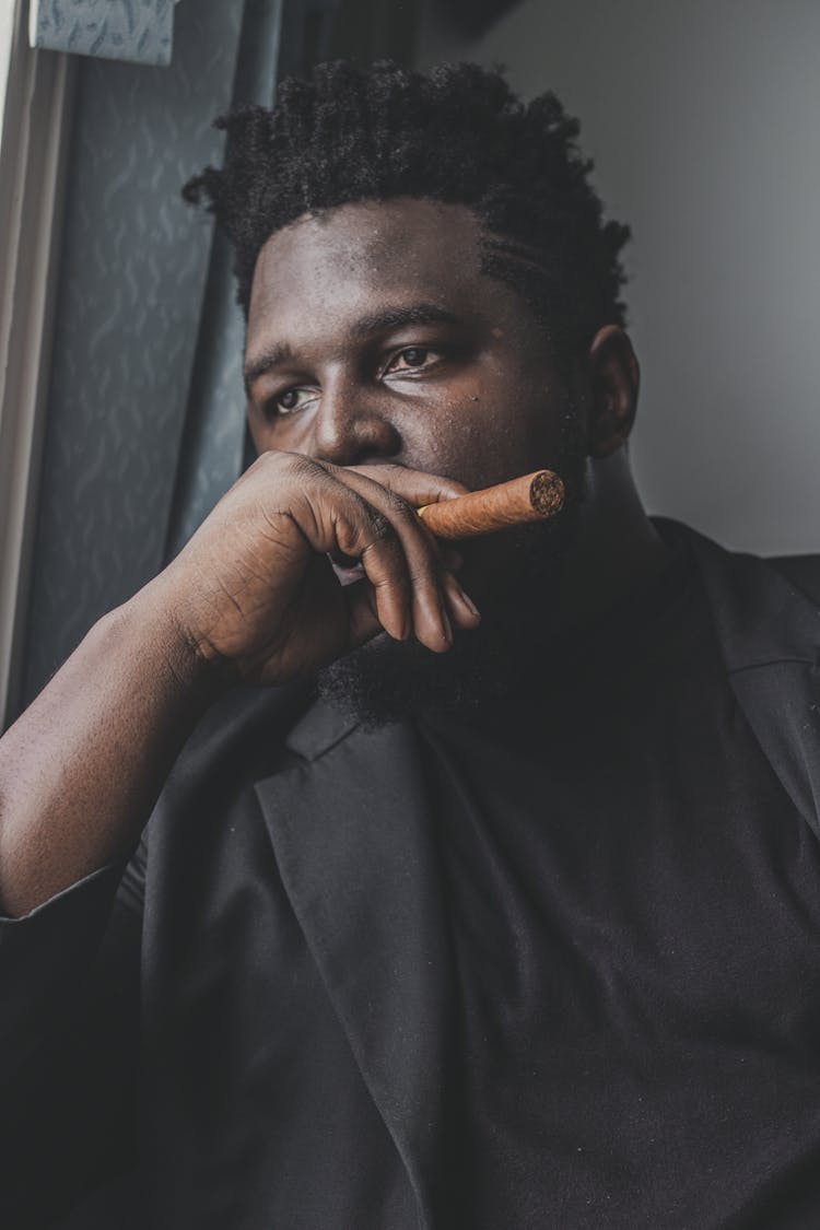 Stylish Pondering Black Businessman With Cigar In Office