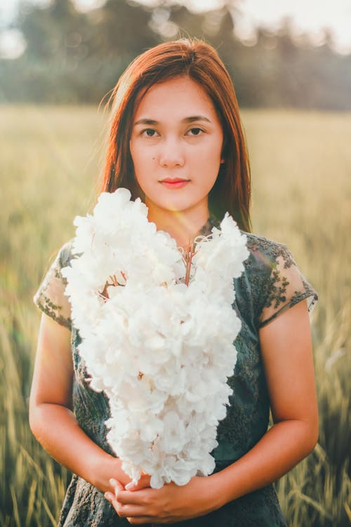 Free Asian woman with white floral branches in field Stock Photo