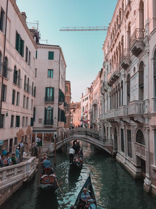 Free People Riding on Boat on River Between Buildings Stock Photo