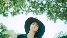 一位亚洲妇女戴着帽子，闭着眼睛，在户外大自然中享受阳光的肖像
