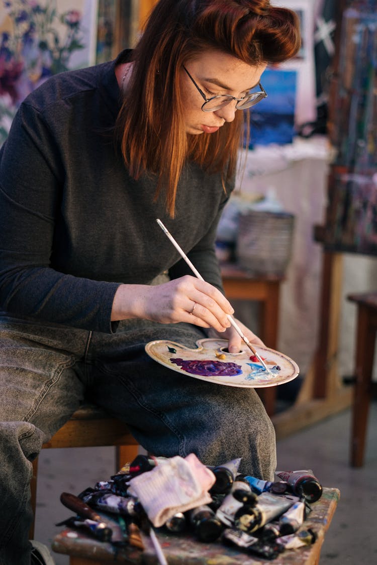 A Woman Mixing Acrylic Paint On A Palette