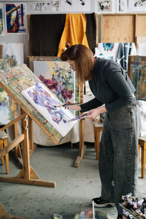 A Woman Painting on a Canvas inside Her Workshop