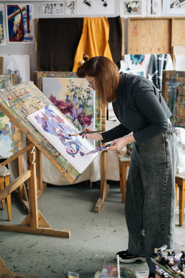 A Woman Painting On A Canvas Inside Her Workshop