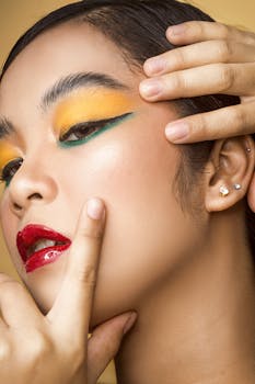Close-up portrait of a woman showcasing vibrant and artistic makeup with yellow eyeshadow and red lips.