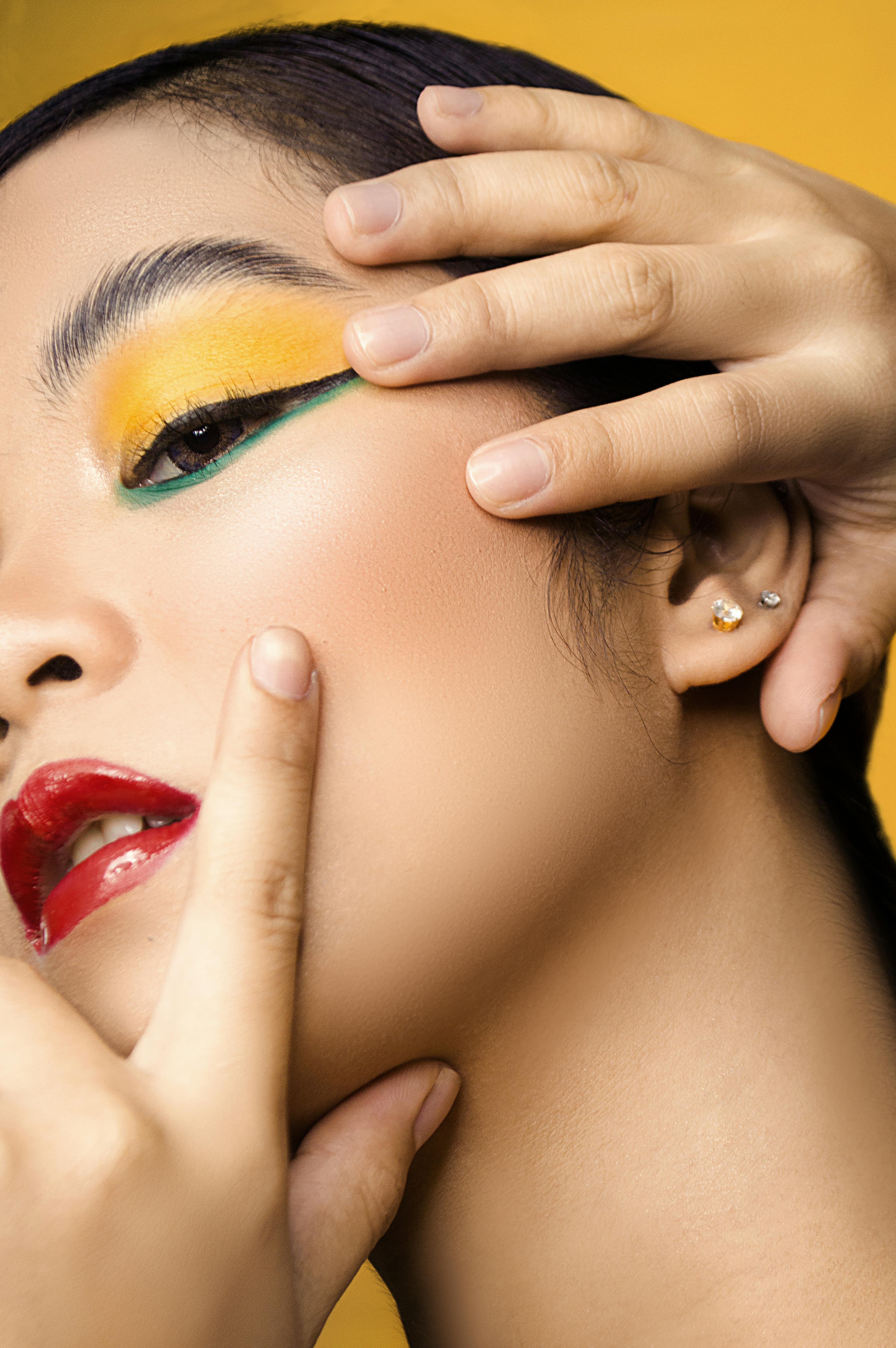 Artistic close-up portrait showcasing vibrant makeup on a woman with a focus on colorful eyeshadow and red lips.