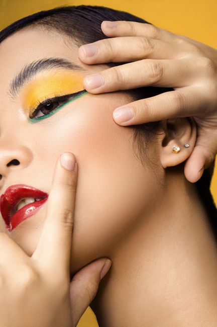 Artistic close-up portrait showcasing vibrant makeup on a woman with a focus on colorful eyeshadow and red lips.