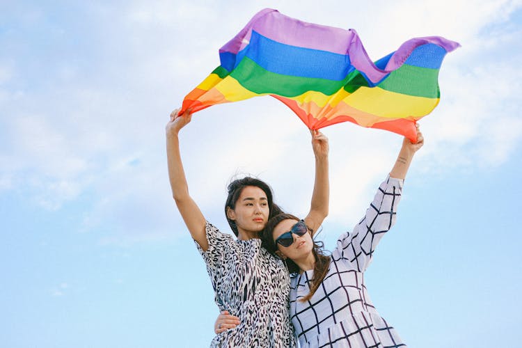 A Couple Waving A Rainbow Flag